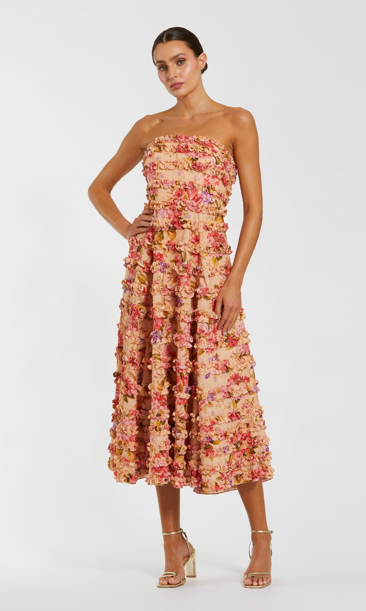 A woman wears the Mac Duggal 8262 Midi Floral Wedding Guest Dress in pink, red, and peach tones, styled with metallic high-heeled sandals—an elegant choice for attending a wedding.